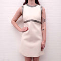 White Celine runway dress with silver embellishments worn by a person against a white brick wall.